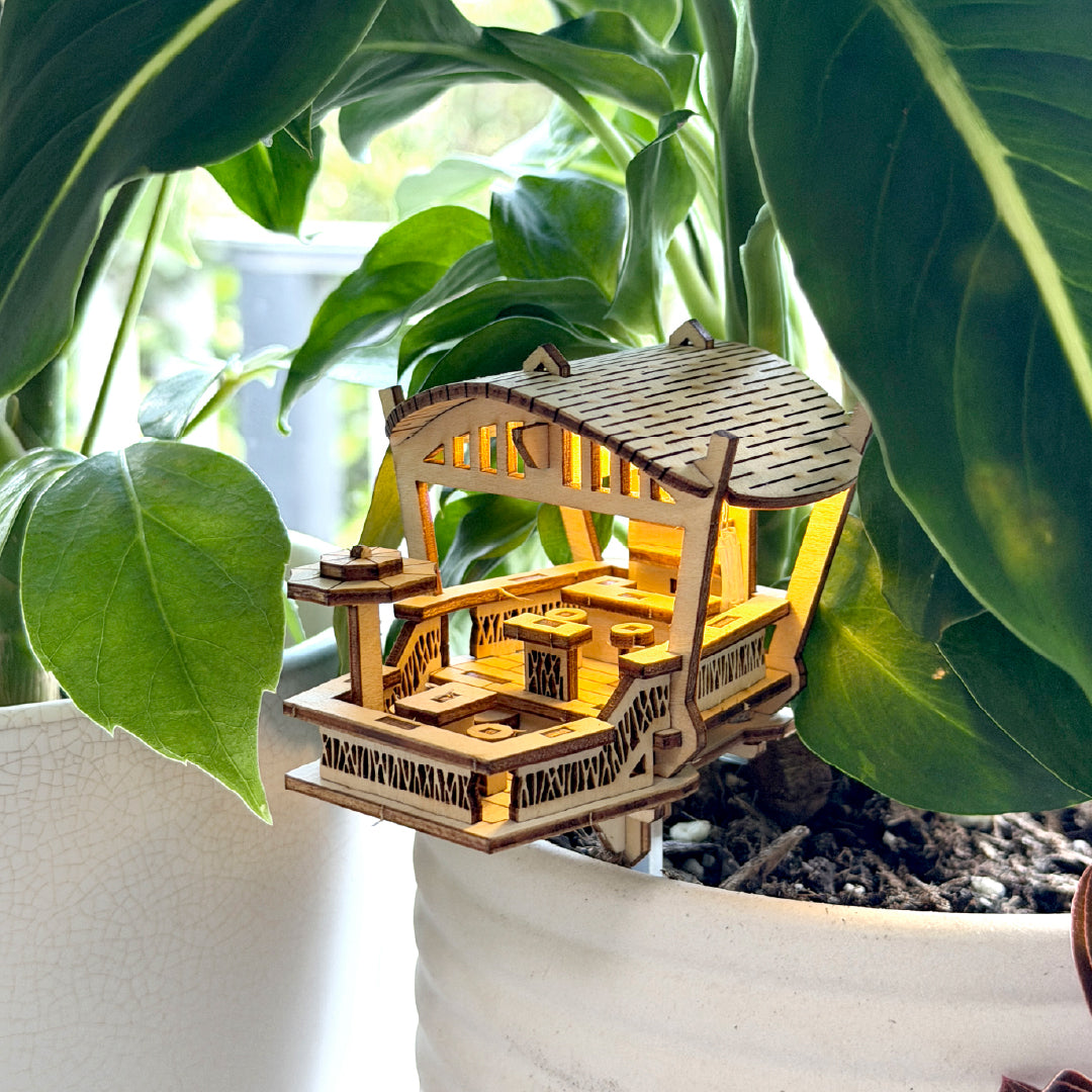 Tiny Treehouses 3D Puzzle Wooden Beach Bar Mini Tiny Treehouse 3D Puzzles nestled in a pot plant model of a traditional Japanese house with green leaves in the background