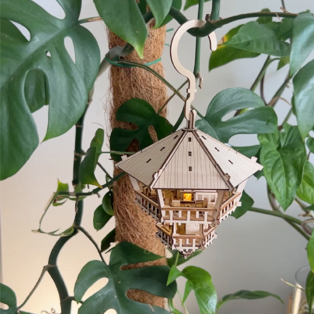 Tiny Treehouses 3D Puzzle Wooden model hanging from a branch with green leaves in the background