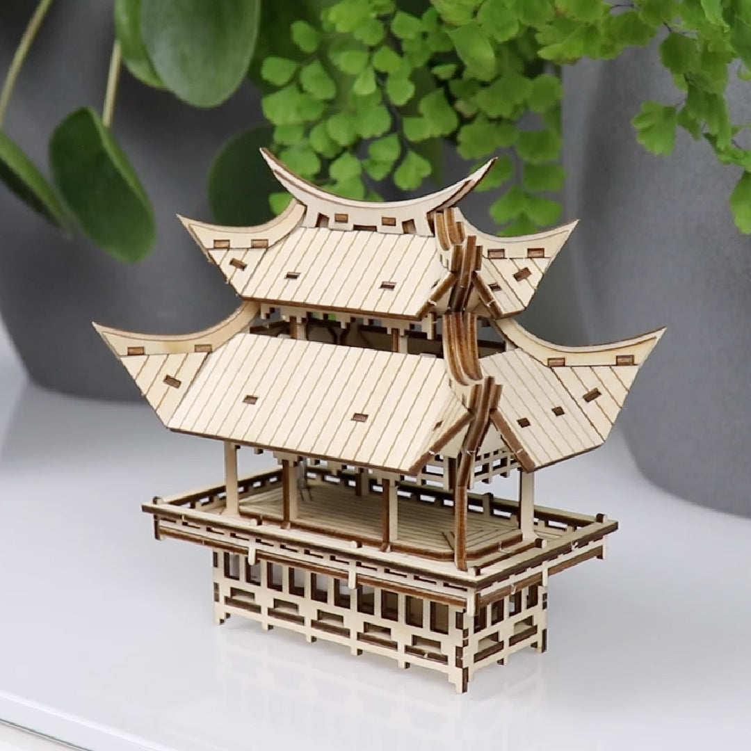 Tiny Treehouses 3D Puzzle Wooden Tiny Treehouse 3D Puzzles model of a traditional Japanese pagoda on a white surface with green plants in the background