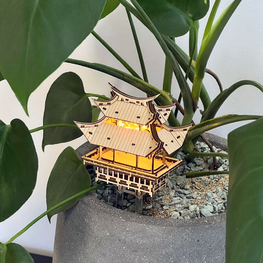 Tiny Treehouses 3D Puzzle Wooden Tiny Treehouse 3D Puzzles pagoda model with glowing interior, placed among green leaves