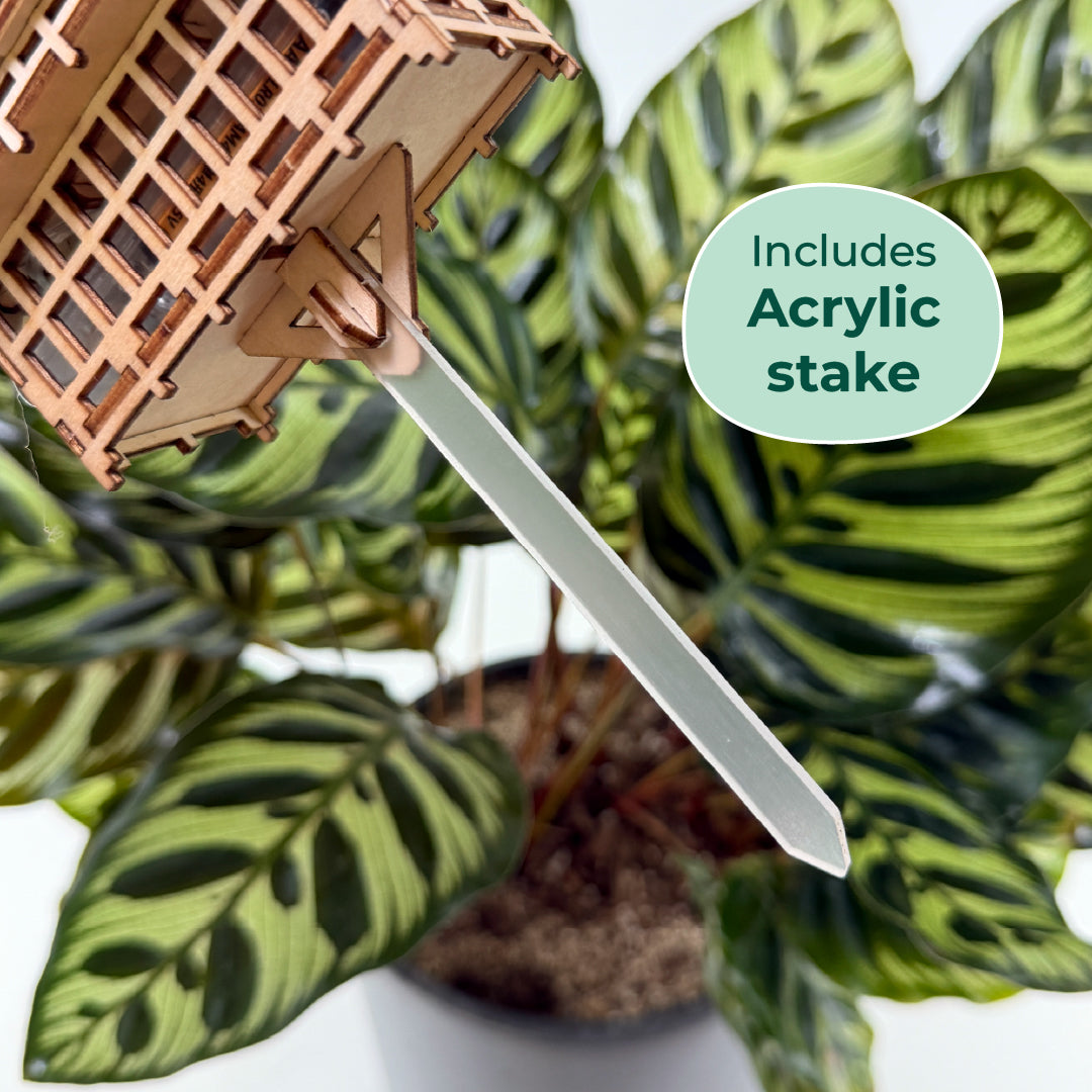 Tiny Treehouses 3D Puzzle Decorative Tiny Treehouse 3D Puzzles with plant stake in acrylic to go into pot soil, set against a green leafy background.