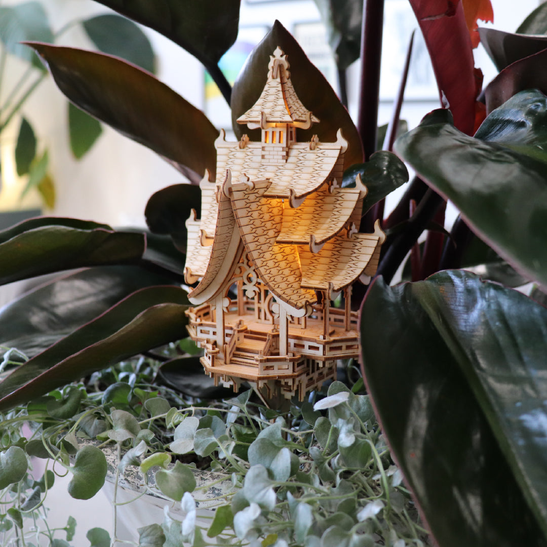 Tiny Treehouses 3D Puzzle Wooden Tiny Treehouse 3D Puzzle pagoda model with a light inside, surrounded by green plants